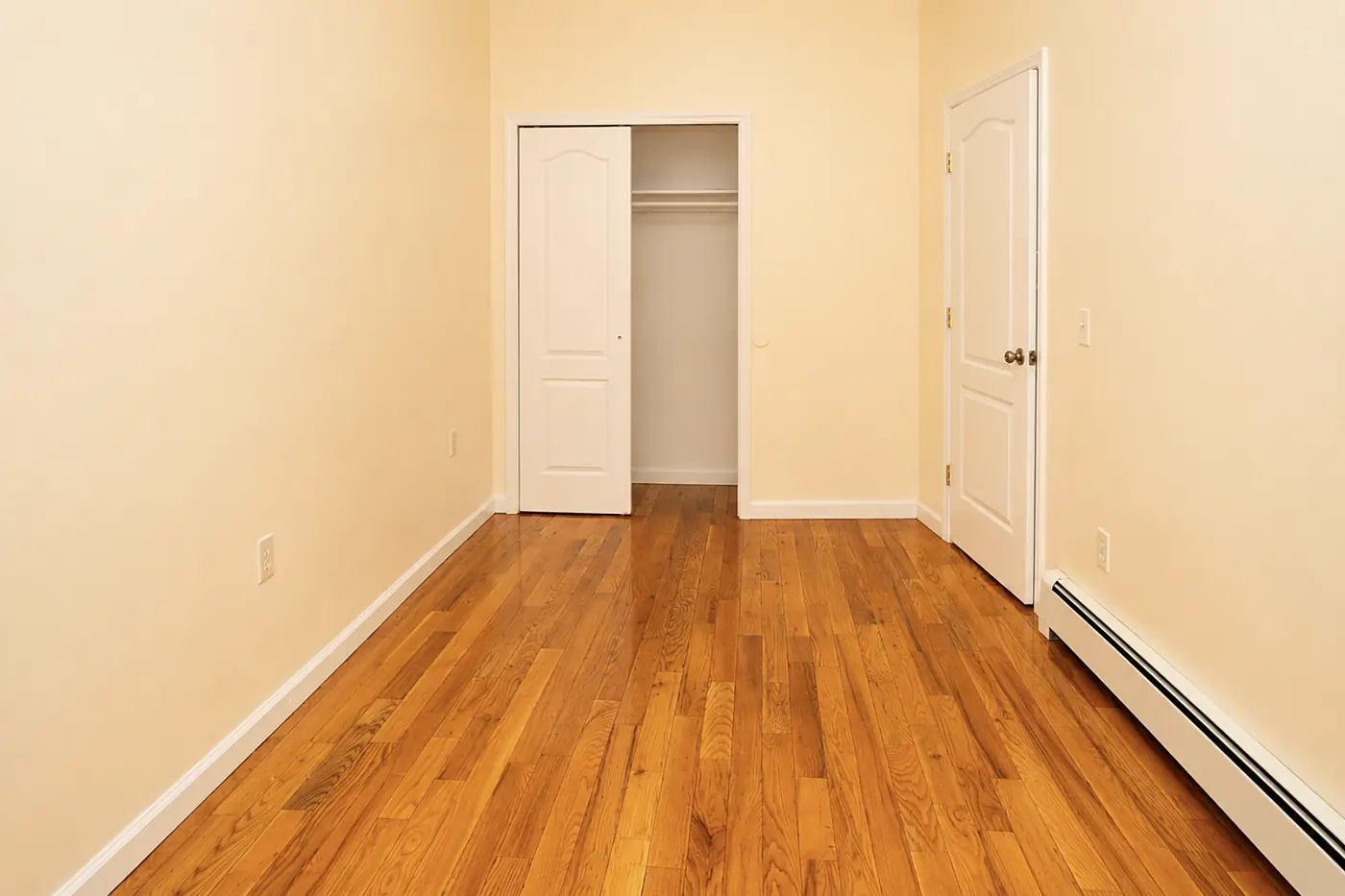 First bedroom with a double closet and hardwood floors